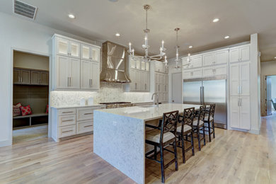 Eat-in kitchen - large contemporary galley light wood floor eat-in kitchen idea in Oklahoma City with an undermount sink, recessed-panel cabinets, white cabinets, quartzite countertops, white backsplash, stone tile backsplash, stainless steel appliances and an island