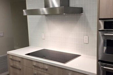 Example of a large minimalist l-shaped eat-in kitchen design in Los Angeles with an undermount sink, flat-panel cabinets, light wood cabinets, gray backsplash, ceramic backsplash, stainless steel appliances and an island
