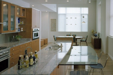 Photo of a large modern l-shaped kitchen/diner in Cincinnati with a double-bowl sink, flat-panel cabinets, medium wood cabinets, marble worktops, stainless steel appliances, light hardwood flooring, an island, grey splashback, stone slab splashback and brown floors.
