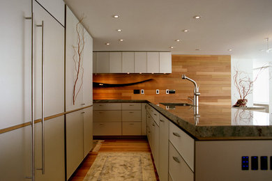 Photo of a medium sized contemporary l-shaped kitchen/diner in Vancouver with a submerged sink, glass-front cabinets, white cabinets, granite worktops, brown splashback, medium hardwood flooring and a breakfast bar.