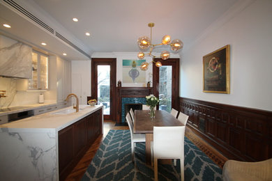Example of a mid-sized transitional galley medium tone wood floor and brown floor eat-in kitchen design in New York with an undermount sink, raised-panel cabinets, white cabinets, marble countertops, white backsplash, marble backsplash, stainless steel appliances and an island