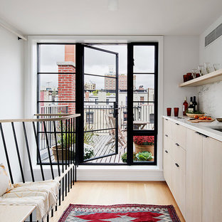 Immagine di una piccola cucina scandinava con lavello sottopiano, ante lisce, ante in legno chiaro, paraspruzzi bianco, parquet chiaro e top bianco