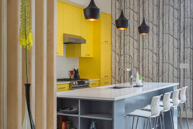 This is an example of a large scandinavian l-shaped kitchen/diner in New York with a built-in sink, flat-panel cabinets, yellow cabinets, composite countertops, white splashback, metro tiled splashback, stainless steel appliances, dark hardwood flooring, an island, brown floors and white worktops.