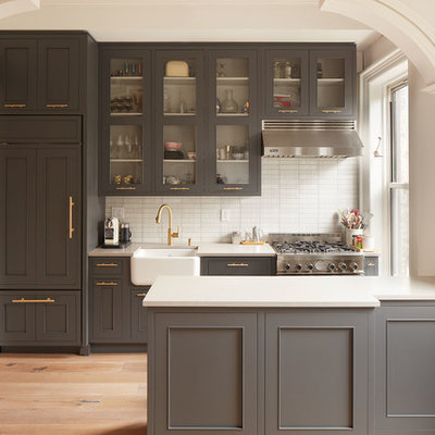 Large transitional single-wall light wood floor and beige floor open concept kitchen photo in New York with a farmhouse sink, gray cabinets, white backsplash, stainless steel appliances, a peninsula, quartz countertops, matchstick tile backsplash and recessed-panel cabinets