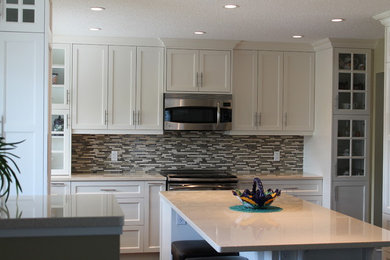 This is an example of a large traditional u-shaped kitchen/diner in Calgary with a submerged sink, shaker cabinets, white cabinets, limestone worktops, multi-coloured splashback, matchstick tiled splashback, stainless steel appliances and an island.