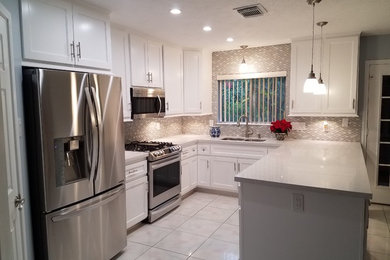 Example of a large trendy u-shaped ceramic tile and gray floor enclosed kitchen design in Houston with a double-bowl sink, recessed-panel cabinets, white cabinets, solid surface countertops, multicolored backsplash, glass tile backsplash, stainless steel appliances and a peninsula
