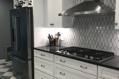 Enclosed kitchen - large traditional galley marble floor and gray floor enclosed kitchen idea in New York with an undermount sink, shaker cabinets, white cabinets, quartz countertops, gray backsplash, marble backsplash, stainless steel appliances, no island and gray countertops