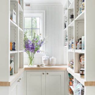 Exemple d'une arrière-cuisine chic en U avec un placard sans porte, des portes de placard blanches, un plan de travail en bois et une crédence blanche.