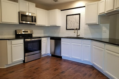 Design ideas for a medium sized traditional u-shaped kitchen/diner in Austin with a submerged sink, recessed-panel cabinets, white cabinets, engineered stone countertops, white splashback, stainless steel appliances, dark hardwood flooring, no island and brown floors.