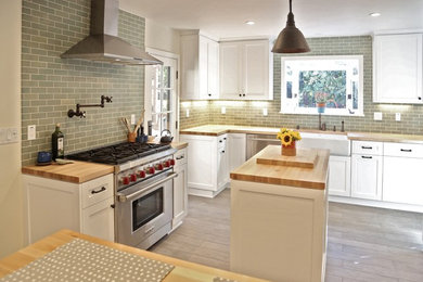 Mid-sized trendy u-shaped ceramic tile eat-in kitchen photo in Los Angeles with a farmhouse sink, shaker cabinets, white cabinets, wood countertops, green backsplash, ceramic backsplash, stainless steel appliances and an island
