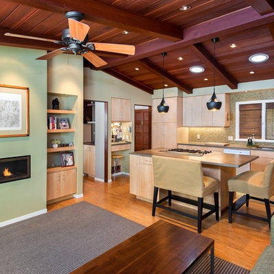 Inspiration for a mid-sized transitional l-shaped light wood floor and beige floor open concept kitchen remodel in San Francisco with flat-panel cabinets, light wood cabinets, metallic backsplash, an undermount sink, solid surface countertops, stainless steel appliances and an island
