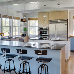 Foto di una grande cucina minimalista con lavello sottopiano, ante lisce, elettrodomestici in acciaio inossidabile, parquet chiaro, ante blu, isola e pavimento marrone