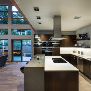 Immagine di una cucina contemporanea con lavello sottopiano, ante lisce, ante in legno bruno, paraspruzzi bianco, elettrodomestici in acciaio inossidabile e pavimento in legno massello medio