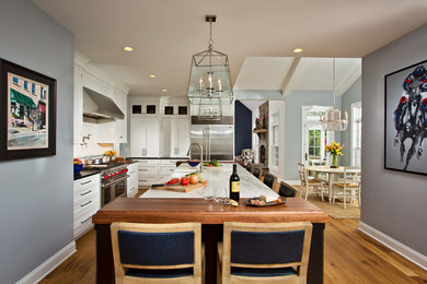 Inspiration för ett vintage linjärt kök, med en rustik diskho, luckor med profilerade fronter, vita skåp, marmorbänkskiva, vitt stänkskydd, rostfria vitvaror, mellanmörkt trägolv och en köksö