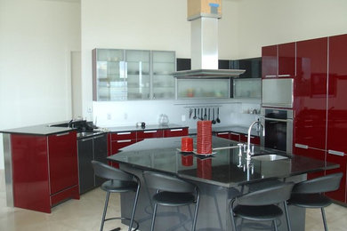 Inredning av ett modernt stort kök, med en undermonterad diskho, släta luckor, röda skåp, bänkskiva i kvarts, marmorgolv, en köksö och beiget golv