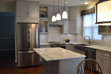 Mid-sized transitional u-shaped medium tone wood floor and brown floor eat-in kitchen photo in DC Metro with shaker cabinets, gray cabinets, quartz countertops, white backsplash, an island, white countertops, a farmhouse sink, stainless steel appliances and subway tile backsplash