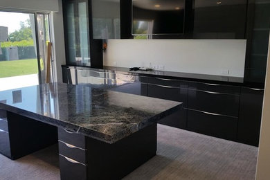 Inspiration for a small contemporary single-wall carpeted and gray floor open concept kitchen remodel in Los Angeles with granite countertops, an island, flat-panel cabinets and black cabinets