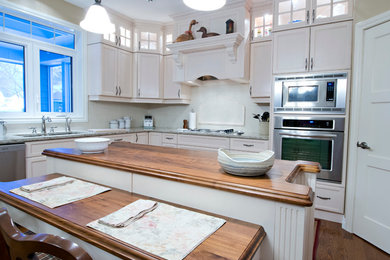 Bild på ett mellanstort vintage kök, med en undermonterad diskho, skåp i shakerstil, vita skåp, träbänkskiva, vitt stänkskydd, rostfria vitvaror, mellanmörkt trägolv, en köksö och stänkskydd i keramik