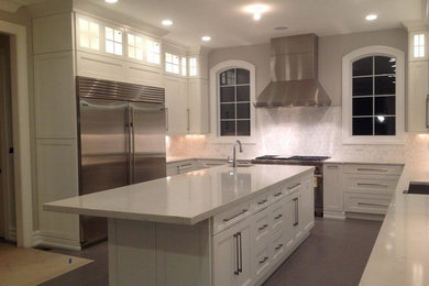 Example of a mid-sized transitional u-shaped concrete floor and gray floor eat-in kitchen design in New York with an undermount sink, recessed-panel cabinets, white cabinets, marble countertops, white backsplash, porcelain backsplash, stainless steel appliances and an island