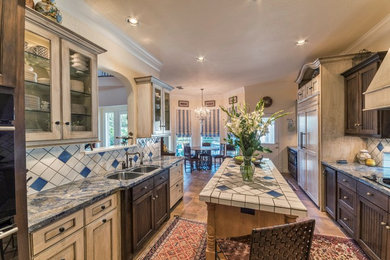 Mid-sized eclectic galley terra-cotta tile eat-in kitchen photo in New Orleans with an undermount sink, beaded inset cabinets, distressed cabinets, white backsplash, ceramic backsplash, paneled appliances, granite countertops and an island