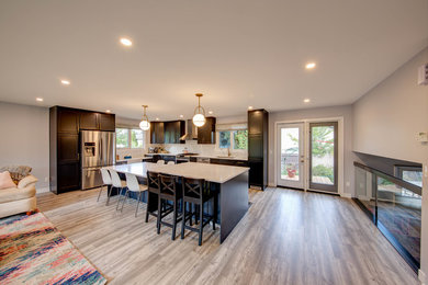 Mid-sized transitional l-shaped laminate floor and brown floor open concept kitchen photo in Edmonton with a single-bowl sink, shaker cabinets, blue cabinets, quartz countertops, white backsplash, ceramic backsplash, stainless steel appliances, an island and white countertops