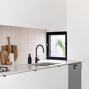 Ejemplo de cocina de galera, actual, pequeña, abierta, con fregadero bajoencimera, puertas de armario blancas, encimera de madera, salpicadero rosa, salpicadero de azulejos de cerámica, electrodomésticos de acero inoxidable, suelo de terrazo, una isla, suelo gris y encimeras marrones