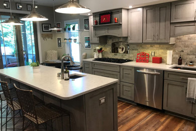 Example of a large arts and crafts u-shaped laminate floor and brown floor eat-in kitchen design in Louisville with an undermount sink, shaker cabinets, gray cabinets, quartzite countertops, gray backsplash, stone tile backsplash, stainless steel appliances, an island and white countertops