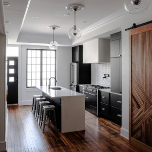 Mid-sized contemporary eat-in kitchen designs - Eat-in kitchen - mid-sized contemporary galley medium tone wood floor, brown floor and tray ceiling eat-in kitchen idea in Baltimore with an undermount sink, flat-panel cabinets, black cabinets, quartz countertops, white backsplash, brick backsplash, stainless steel appliances, an island and white countertops