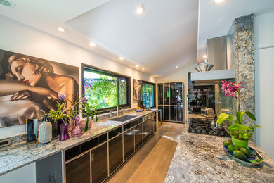 Example of a large trendy galley medium tone wood floor and brown floor open concept kitchen design in San Francisco with an undermount sink, flat-panel cabinets, black cabinets, granite countertops, multicolored backsplash, stone slab backsplash, stainless steel appliances and no island