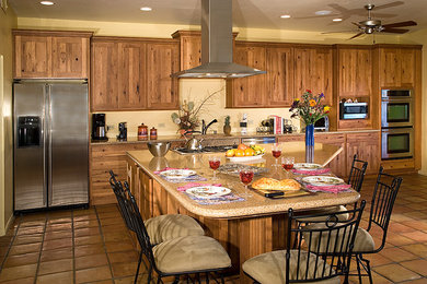 フェニックスにあるお手頃価格の広いラスティックスタイルのおしゃれなキッチン (ダブルシンク、シェーカースタイル扉のキャビネット、中間色木目調キャビネット、ベージュキッチンパネル、シルバーの調理設備、テラコッタタイルの床) の写真