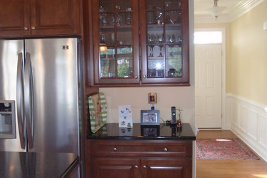Example of a mid-sized classic l-shaped eat-in kitchen design in Philadelphia with raised-panel cabinets, dark wood cabinets, granite countertops, stainless steel appliances and an island