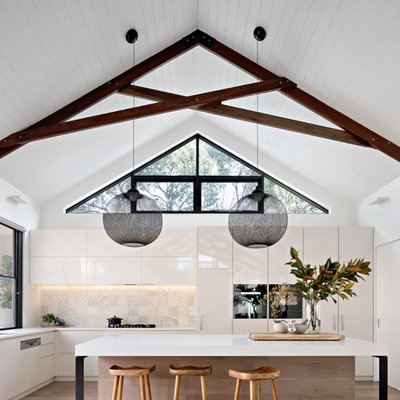 Mid-sized trendy l-shaped medium tone wood floor and brown floor kitchen photo in Melbourne with flat-panel cabinets, white cabinets, beige backsplash, an undermount sink, paneled appliances and an island