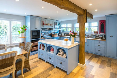 Design ideas for a farmhouse kitchen/diner in Kent with shaker cabinets, an island and blue worktops.