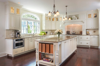 Example of a large classic l-shaped dark wood floor eat-in kitchen design in Providence with an undermount sink, raised-panel cabinets, white cabinets, granite countertops, multicolored backsplash, matchstick tile backsplash, stainless steel appliances and an island