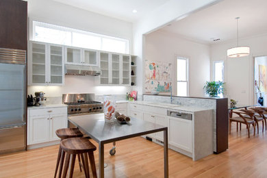Inspiration for a large modern l-shaped light wood floor eat-in kitchen remodel in San Francisco with a drop-in sink, shaker cabinets, white cabinets, marble countertops, white backsplash, stone tile backsplash, stainless steel appliances and an island