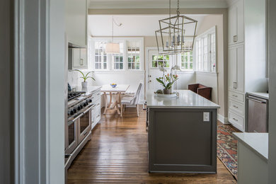 Example of a mid-sized classic u-shaped medium tone wood floor and brown floor eat-in kitchen design in Jackson with shaker cabinets, white cabinets, marble countertops, white backsplash, subway tile backsplash, stainless steel appliances and an island