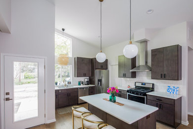 Example of a mid-sized trendy l-shaped medium tone wood floor and brown floor eat-in kitchen design in Austin with a double-bowl sink, flat-panel cabinets, dark wood cabinets, solid surface countertops, white backsplash, ceramic backsplash, stainless steel appliances and an island