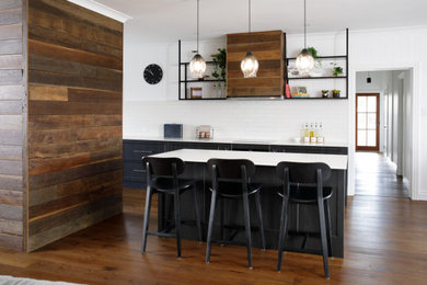 Inspiration for a large industrial medium tone wood floor and brown floor kitchen remodel in Brisbane with an undermount sink, shaker cabinets, black cabinets, quartz countertops, white backsplash, subway tile backsplash, black appliances, an island and white countertops