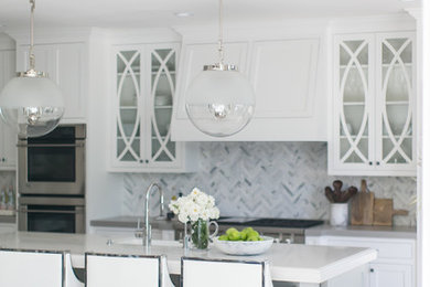 Kitchen - coastal kitchen idea in San Diego with white cabinets, quartz countertops, marble backsplash, stainless steel appliances and an island