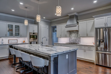 Large l-shaped medium tone wood floor and brown floor open concept kitchen photo in Dallas with an undermount sink, shaker cabinets, gray cabinets, marble countertops, white backsplash, subway tile backsplash, stainless steel appliances and an island