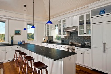 Exempel på ett mellanstort klassiskt linjärt kök med öppen planlösning, med en enkel diskho, luckor med infälld panel, vita skåp, bänkskiva i täljsten, blått stänkskydd, stänkskydd i keramik, integrerade vitvaror, mellanmörkt trägolv och en halv köksö