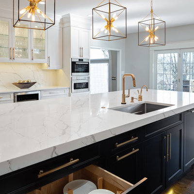 Large transitional u-shaped dark wood floor and brown floor kitchen photo in Other with an undermount sink, flat-panel cabinets, white cabinets, quartz countertops, white backsplash, stone slab backsplash, stainless steel appliances, an island and white countertops