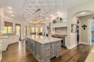 Inspiration for a large transitional u-shaped medium tone wood floor and brown floor eat-in kitchen remodel in Phoenix with an undermount sink, beaded inset cabinets, white cabinets, marble countertops, gray backsplash, ceramic backsplash, paneled appliances, an island and multicolored countertops