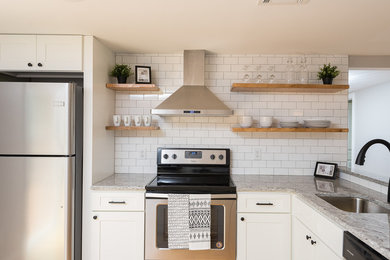 Small transitional l-shaped light wood floor and brown floor open concept kitchen photo in Boston with a single-bowl sink, recessed-panel cabinets, white cabinets, granite countertops, white backsplash, subway tile backsplash, black appliances and a peninsula