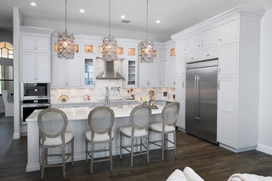 Imagen de cocina clásica renovada con puertas de armario blancas, salpicadero blanco, electrodomésticos de acero inoxidable y suelo marrón