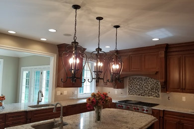 Eat-in kitchen - mid-sized traditional u-shaped eat-in kitchen idea in Philadelphia with an undermount sink, raised-panel cabinets, medium tone wood cabinets, granite countertops, beige backsplash, ceramic backsplash, stainless steel appliances and an island