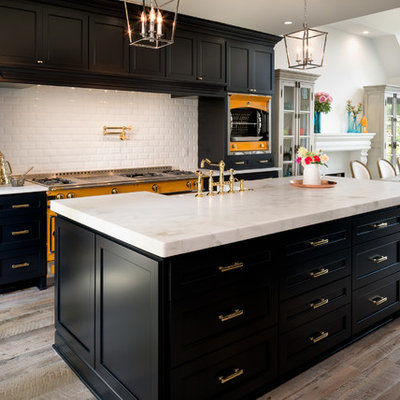 Example of a large transitional light wood floor eat-in kitchen design in Charlotte with a farmhouse sink, marble countertops, white backsplash, subway tile backsplash, shaker cabinets, colored appliances and two islands