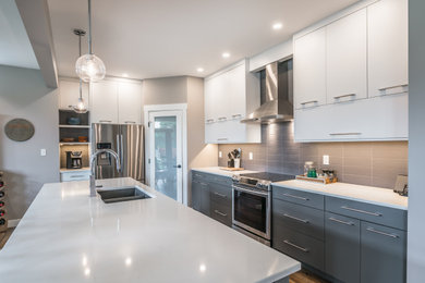 Example of a mid-sized trendy u-shaped laminate floor and beige floor open concept kitchen design in Vancouver with an undermount sink, flat-panel cabinets, white cabinets, quartz countertops, gray backsplash, porcelain backsplash, stainless steel appliances, an island and white countertops