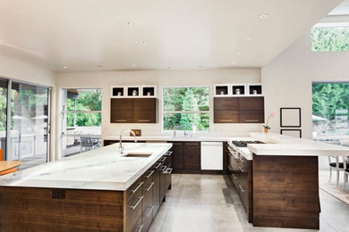 Example of a large trendy l-shaped concrete floor eat-in kitchen design in Los Angeles with an undermount sink, flat-panel cabinets, dark wood cabinets, marble countertops, stainless steel appliances and an island