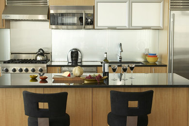 Foto di una grande cucina minimalista in acciaio con elettrodomestici in acciaio inossidabile, lavello sottopiano, ante lisce, ante in legno scuro, top in granito, paraspruzzi grigio e pavimento in legno massello medio